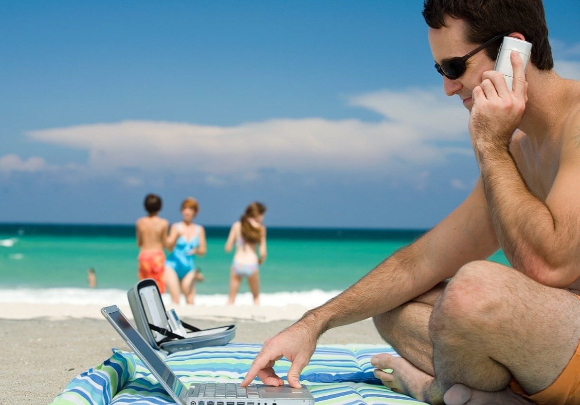 man working on a laptop at the beach